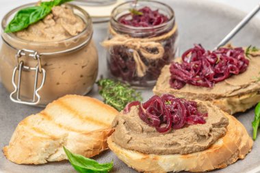 Karaciğer ezmesi ve kırsal bir tabakta karamelize soğanla kaplı kızarmış ekmek dilimleri..