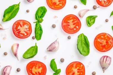 Fesleğen yapraklı taze domates dilimleri, sarımsak karanfilleri ve beyaz arka planda biberli mısır. en üstteki görünüm.