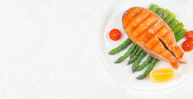 Izgara somon fileto, kuşkonmaz, kiraz domatesleri, ve beyaz tabakta limon, uzun pankart formatı. Üst Manzara. Boşluğu kopyala.