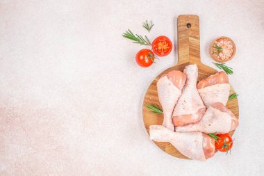 Tahtada çiğ tavuk budu, domates, biberiye ve tuz. Üst Manzara. Boşluğu kopyala.