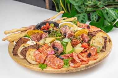 Tahta bir tabakta çeşitli et, peynir, ekmek ve sebzeler ile şarküteri tabağı..