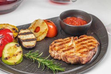 Karışık sebze, ananas, biberiye ve domates sosuyla servis edilen sulu ızgara biftek..