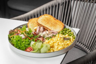 Dengeli kahvaltı tabağı omlet, kızarmış ekmek, taze salata, jambon dilimleri, peynir, salatalık kurdelesi ve yeşil fasulye..