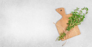 Taze kekik demeti ahşap kesme tahtasına bağlanmış halatla gri taş arka planda fotokopi alanı ile birlikte. Yemek pişirmek için organik bitkiler, doğal baharatlar, yemek şablonu tasarımı..