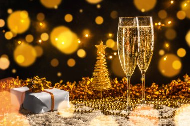 İki şampanya bardağı köpüklü şarap, altın bokeh ışıkları, Noel ağacı süsü ve yılbaşı, Noel, düğün ya da kutlama partisi için şenlikli dekor..