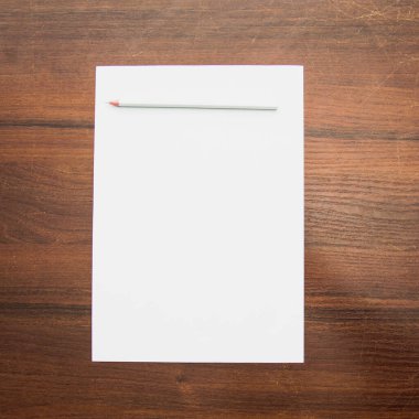 Bir fotoğraf stüdyosundaki güzel bir arka planda boş bir kağıdın üzerinde bir kalem yatıyor.