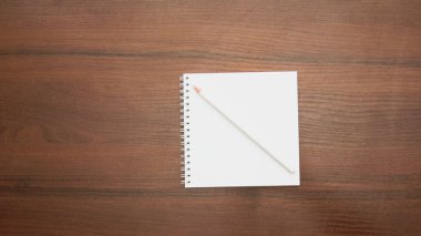 Ahşap zemin üzerinde kalem olan boş bir defter