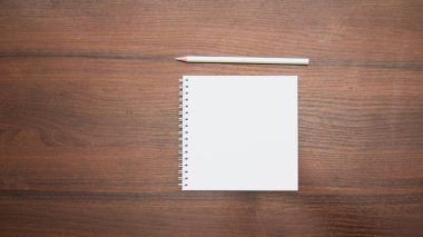 Ahşap zemin üzerinde kalem olan boş bir defter