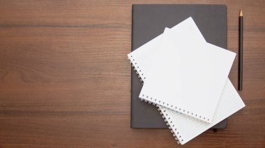 blank notepad with pen and pencil on wooden background