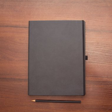 Ahşap zemin üzerinde boş beyaz kağıt kitap ve kalem siyah ve sarı fotoğraf