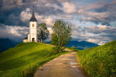 Kirli kırsal yol ve dağ sırtında ikonik alp kilisesi, Aziz Primoz kilisesi, Jamnik köyü, Slovenya, Avrupa