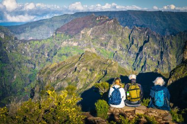 Dağlarda oturan mutlu yaşlı arkadaşlar. Pico do Areeiro tepesinde dinlenen yaşlı yürüyüşçüler Madeira Adası, Portekiz ve Avrupa 'nın güzel manzarasının tadını çıkarıyorlar.