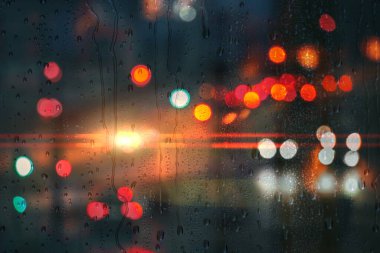 Yağmurlu günlerde pencereye yağmur damlaları ve arka planda sokak ışıkları 