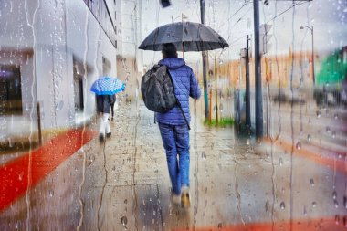 Kışın yağmurlu günlerde elinde şemsiyeyle sokakta yürüyen yayalar. 