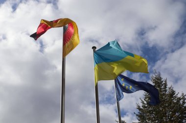 Ukrayna, Almanya ve Avrupa Birliği bayrakları mavi gökyüzüne karşı yan yana dalgalanıyor