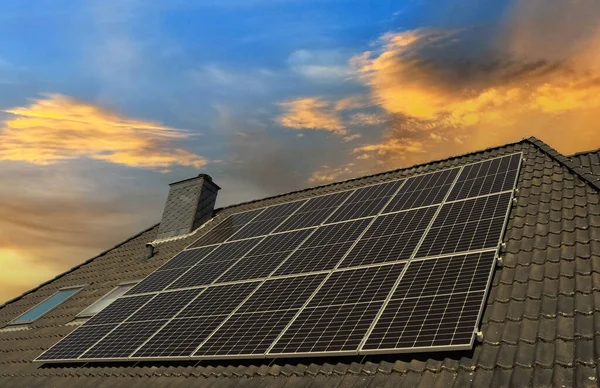日落时在住宅屋顶上生产清洁能源的太阳能电池板 — 图库照片