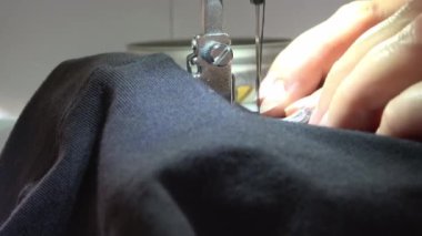 Modern bir dikiş makinesinde çalışan kadın eller bazı kumaşlar ve tekstil ürünleriyle