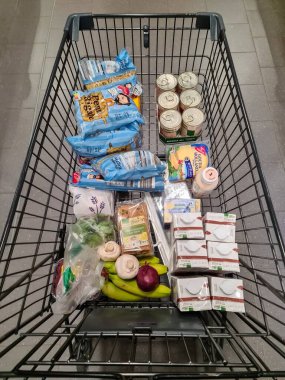 Kiel, Almanya - 25. Kasım 2022: Bir süpermarkette sayısız markalı malzemeyle dolu bir Alman alışveriş vagonuna bakın