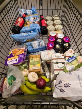 Kiel, Almanya - 25. Kasım 2022: Bir süpermarkette sayısız markalı malzemeyle dolu bir Alman alışveriş vagonuna bakın