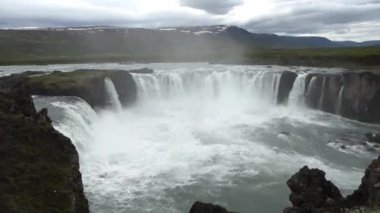 Muhteşem Godafoss şelalesi İzlanda manzarasında kayalar ve otlarla