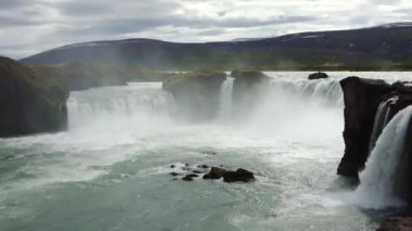 Muhteşem Godafoss şelalesi İzlanda manzarasında kayalar ve otlarla