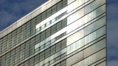 Berlin, Almanya - 03. Ekim 2022: Bir ofis binasının cam cephesinden yansıyan bulutlarla mavi bir yaz gökyüzünün zaman aşımı.