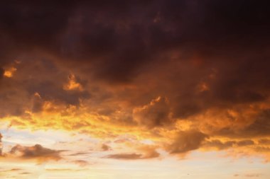 Güneş doğarken ve batarken mavi gökyüzünde turuncu ve sarı bulutlardan oluşan güzel bir manzara.