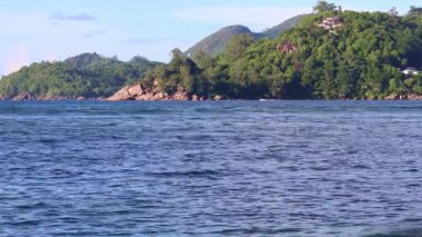 Beautiful view at the beaches of the Seychelles with some splahing water waves and a blue sky