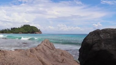 Beautiful view at the beaches of the Seychelles with some splahing water waves and a blue sky