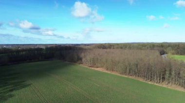 Aerial view of a drone of a forest and farmland with small country roads and farms in between.
