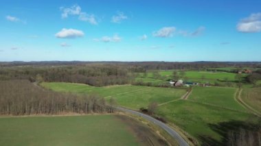 Aerial view of a drone of a forest and farmland with small country roads and farms in between.