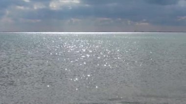 Işıl ışıl suyun seçici odak noktası. Dalgalar, parlak güneş ışığını çok yumuşak bir bokeh ile yansıtıyor.