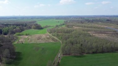 Aerial view of a drone of a forest and farmland with small country roads and farms in between.