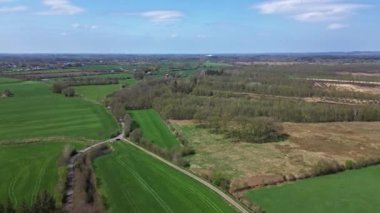 Aerial view of a drone of a forest and farmland with small country roads and farms in between.