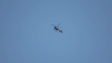 Küçük siyah bir helikopter mavi gökyüzüne doğru bir kavis çiziyor..
