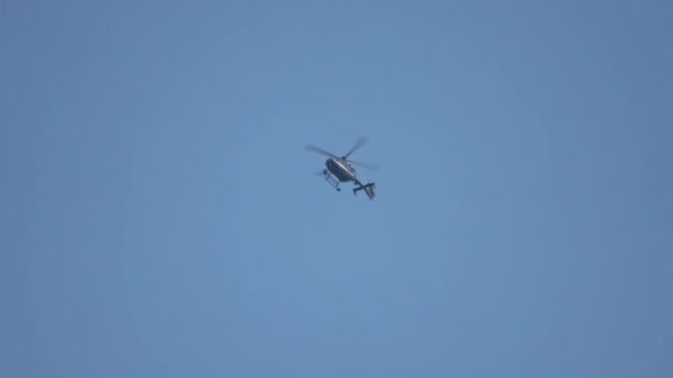 小さな暗いヘリコプターが青い空に向かって曲線を飛ぶ — ストック動画