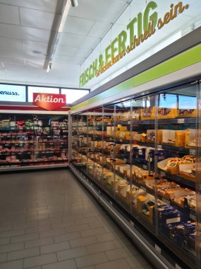 Kiel, Almanya - 27. Eylül 2023: Bir Alman süpermarketinde birçok ürünün bulunduğu büyük bir süpermarket rafı boyunca görüntüle