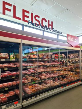 Kiel, Almanya - 27. Eylül 2023: Bir Alman süpermarketinde birçok ürünün bulunduğu büyük bir süpermarket rafı boyunca görüntüle