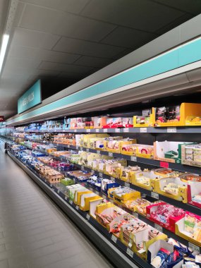 Kiel, Almanya - 27. Eylül 2023: Bir Alman süpermarketinde birçok ürünün bulunduğu büyük bir süpermarket rafı boyunca görüntüle