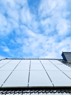 Kar, bir evin çatısında temiz enerji üreten güneş panellerini kapladı