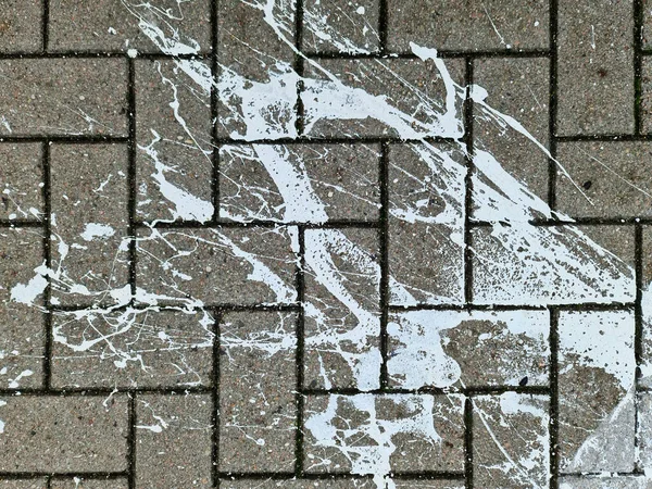 Paving stones from above with paint splatters and splatters of paint on them