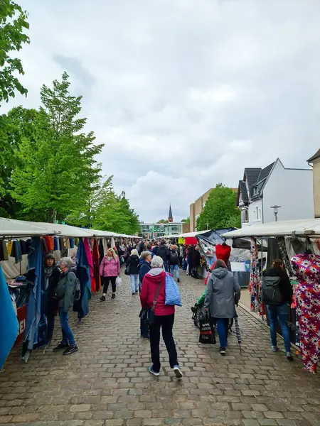 Neumuenster, Almanya - 04. Mayıs 2024: İnsanlar bir çok tezgah ve dükkanla birlikte bir kumaş pazarına bakıyorlar