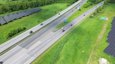 Almanya 'da trafiğin yoğun olduğu ve çevresini çevreleyen yeşil alanların olduğu bir otoyolun insansız hava aracı görüntüsü.