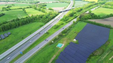Bir Alman otoyolunda insansız hava aracı uçuşu. Çok fazla trafik ve yol kenarında büyük güneş panelleri var..