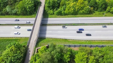 Almanya 'da trafiğin yoğun olduğu ve çevresini çevreleyen yeşil alanların olduğu bir otoyolun insansız hava aracı görüntüsü