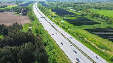 Bir Alman otoyolunda insansız hava aracı uçuşu. Çok fazla trafik ve yol kenarında büyük güneş panelleri var.