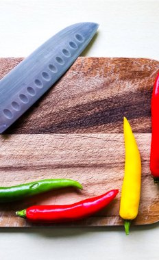 Ahşap kesme tahtasındaki kırmızı biber ve bıçağın izole edilmiş arka planda üst ve perspektif görüntüsü