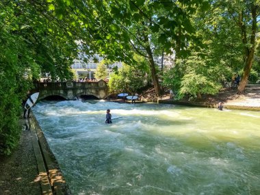 Münih, Almanya - 22 Haziran 2024: Münih 'in merkezindeki Eisbach dalgasında sörfçü