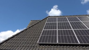 Elektrik üreten bir güneş sisteminin güneş ışığındaki bir yerleşim yerinin çatısındaki görüntüsü..