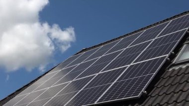 Elektrik üreten bir güneş sisteminin güneş ışığındaki bir yerleşim yerinin çatısındaki görüntüsü..